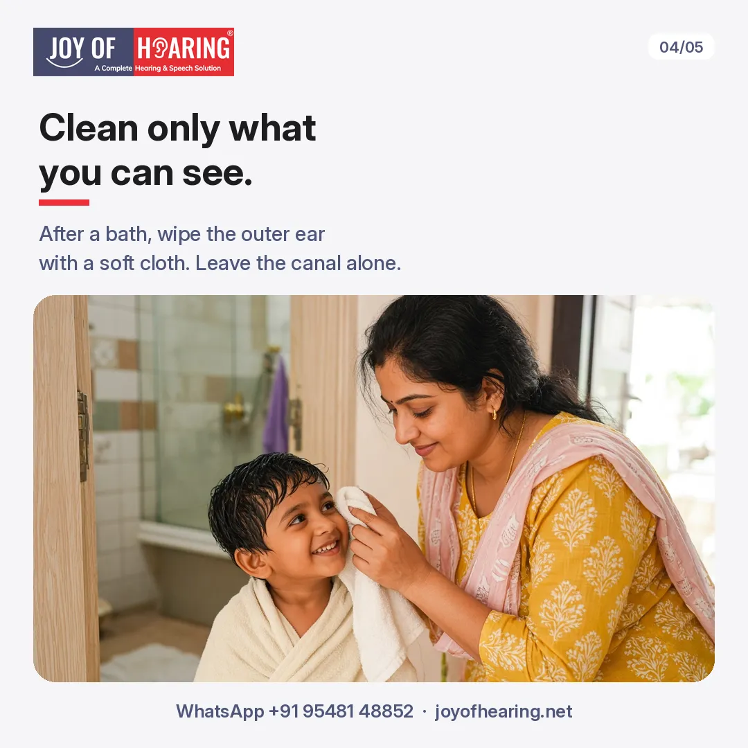 A mother wipes her smiling son's outer ear with a soft towel after his bath.